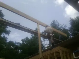 Carpenter setting a ridge beam over a new addition frame — Ice Dam Removal by Roofing Brothers in La Motte