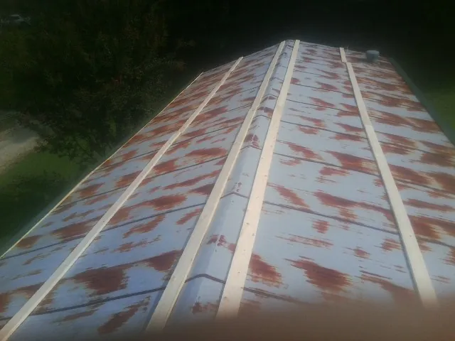 Rusted metal roof panels with new wood purlins before replacement — Storm Damage Roof Repair in La Motte by Roofing Brothers
