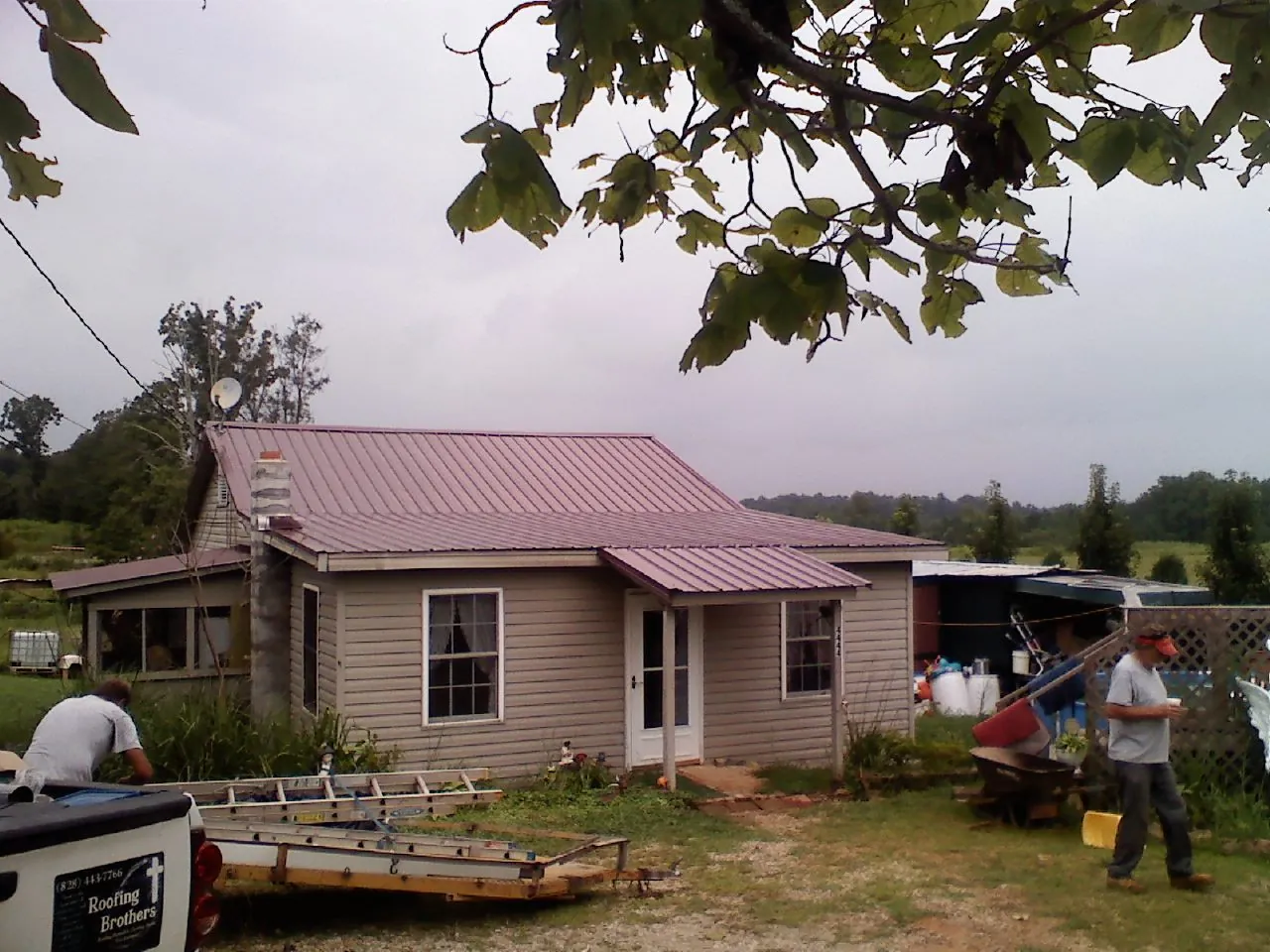 Crew finishing a mauve metal roof on a small farmhouse in La Motte