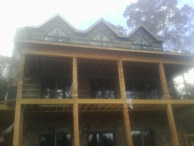 Dormers and porch framing on a large log home under construction — Roof Coating work by our crew in La Motte