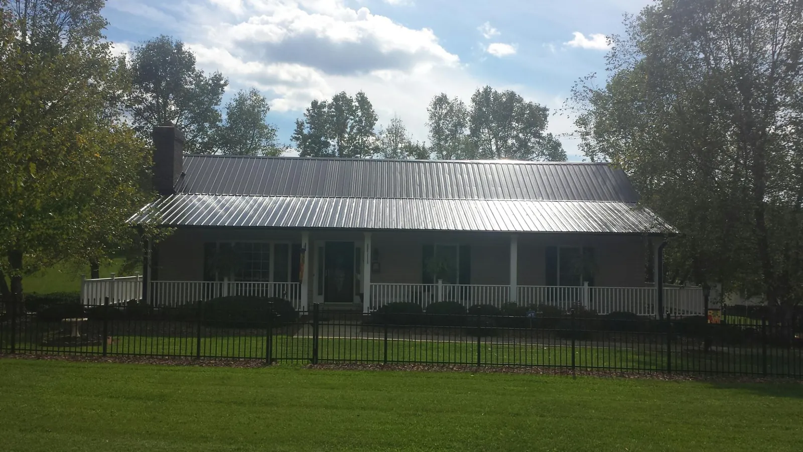 Gray metal roof on a brick ranch with a full width front porch — Gutter Guard Installation work by our crew in La Motte