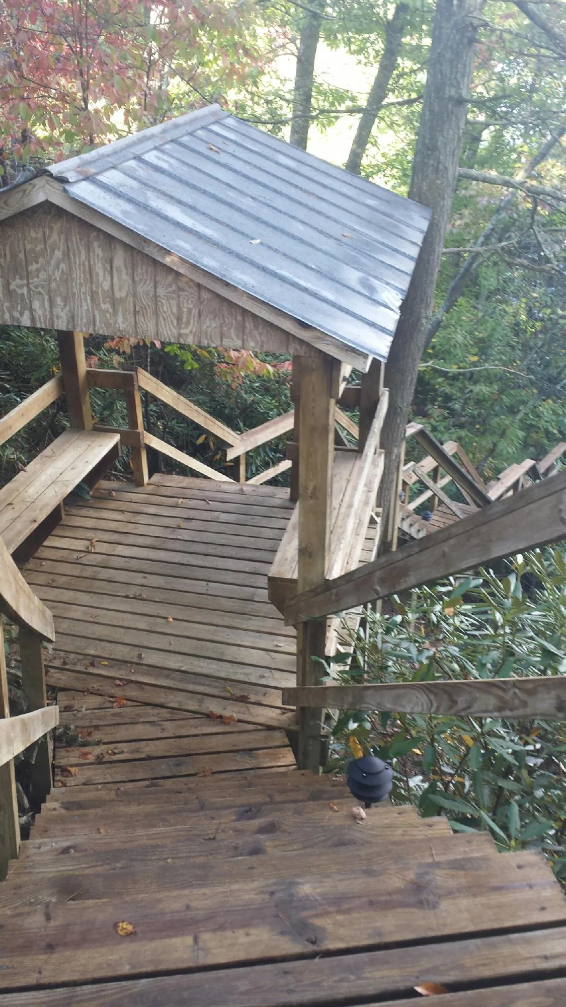 Metal roofed shelter over wooden steps on a wooded walkway — Skylight Repair & Installation work by our crew in La Motte