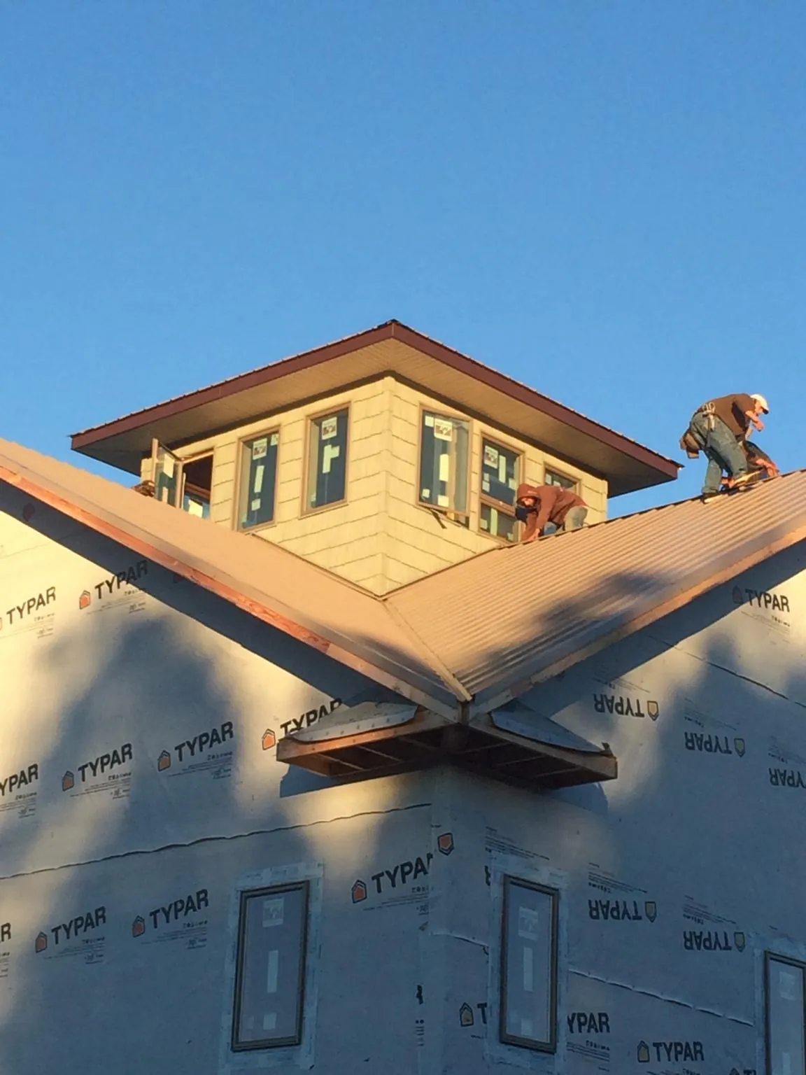 Roofers working around a rooftop cupola on a new metal roof at sunset — Roof Waterproofing in La Motte by Roofing Brothers